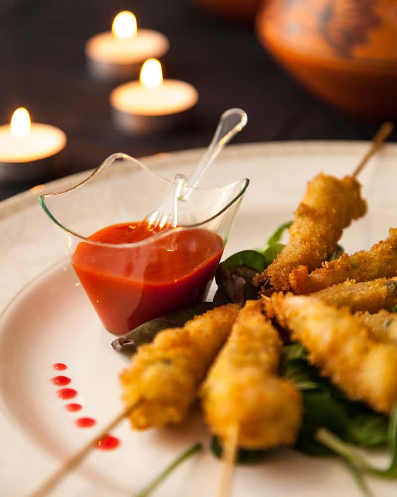 A plate of Indian food on skewers with a dipping sauce.