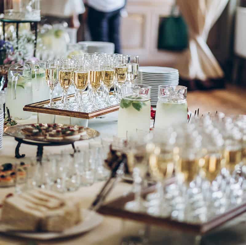 A table with many glasses of champagne and food on it.