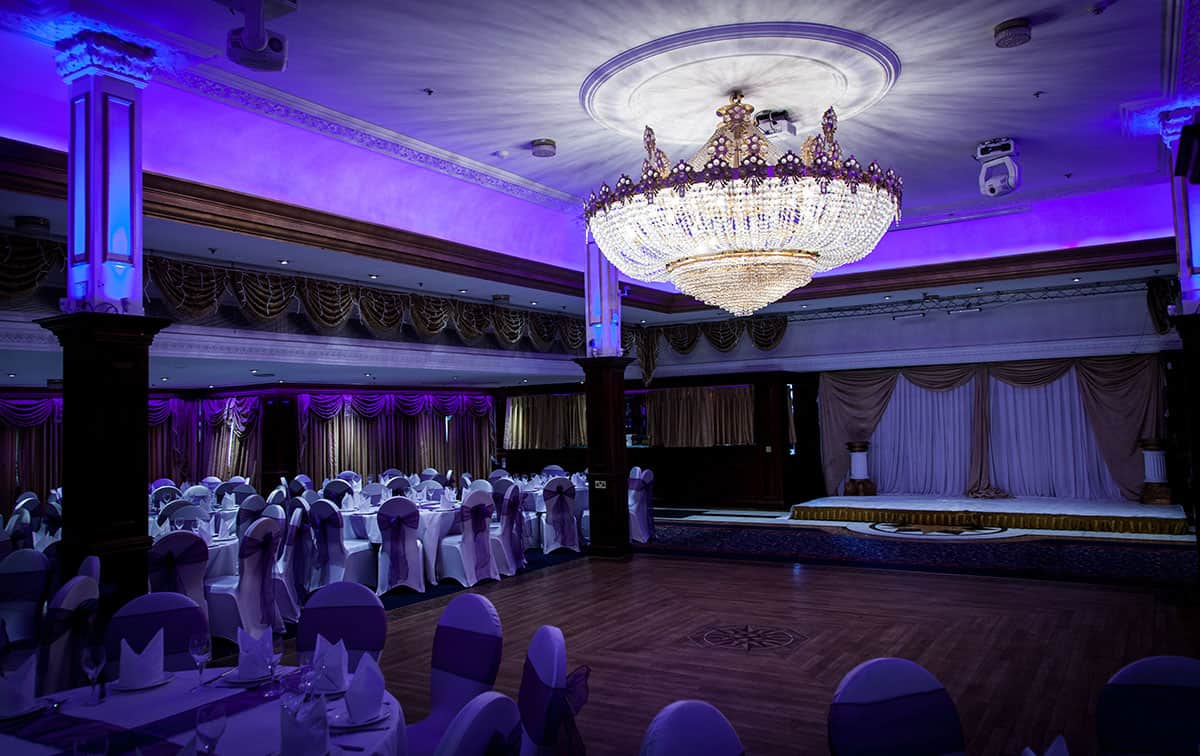 A wedding reception set up with purple lights and a chandelier.
